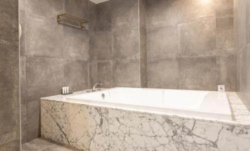 a white bath tub in a bathroom with marble walls at Hotel 99 Prestige in Seoul