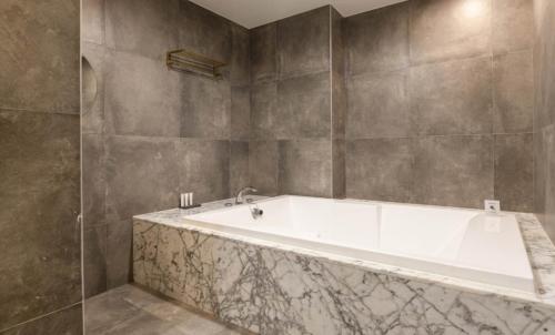 a white tub in a bathroom with gray walls at Hotel 99 Prestige in Seoul