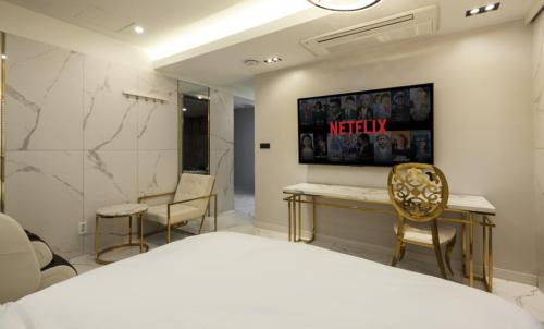 a bedroom with a bed and two chairs and a wall at Hotel 99 Prestige in Seoul