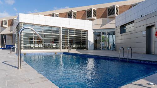 a building with a swimming pool in front of a building at Albergue Las Salinas in San Pedro del Pinatar