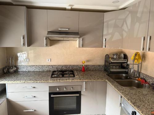 een keuken met witte kasten, een fornuis en een wastafel bij Moul Partma Saidia Joss in Saidia 