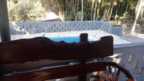 a wooden bench in front of a swimming pool at Juquitiba Chácara Recanto dos Magos Chalé Piscina Fogão a Lenha Churrasqueira in Juquitiba