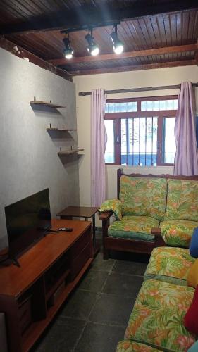 a living room with a couch and a flat screen tv at Juquitiba Chácara Recanto dos Magos Chalé Piscina Fogão a Lenha Churrasqueira in Juquitiba