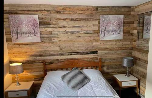 a bedroom with a wooden accent wall with a bed at 284 - Room 6 - Beachfront in Swansea