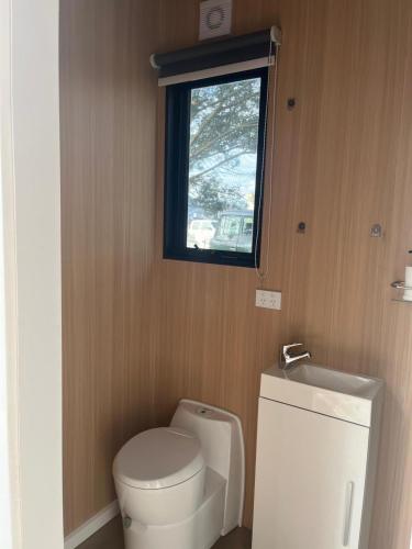 Un pequeño baño con inodoro y ventana. en QueensFerry Farm by the Bay by Tiny Away, en Grantville