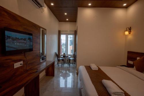 a bedroom with a bed and a television and a table at Hotel Relax Inn Ganga Rishikesh in Rishīkesh