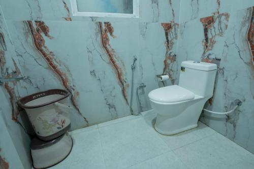 a bathroom with a toilet and a trash can at Hotel Relax Inn Ganga Rishikesh in Rishīkesh