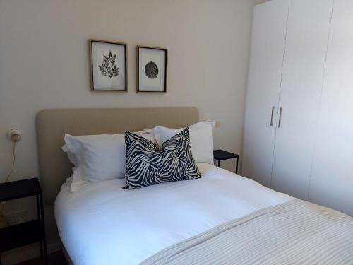 a white bed with a zebra pillow on top of it at 212 The Meadows in George