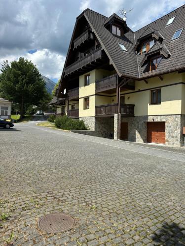 a large building with a black roof on a street at Apartment Tatry Comfort - Tatranská Lomnica in Vysoké Tatry