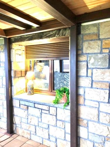 a window on a brick building with a potted plant at Ak-55 Rural House in Villaviciosa