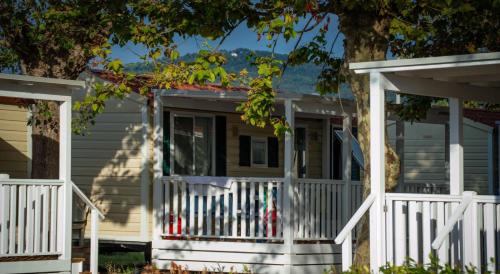 a house with a white fence and a porch at The Beach Camping Village in Marina di Carrara