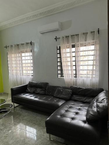 a black leather couch in a living room with two windows at ADISSA's PLACE in Cotonou