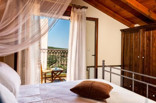 a bedroom with a bed and a balcony with a window at Villa Eftichia in Stalos