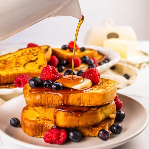 un piatto di french toast con bacche e sciroppo di Neshaz Hotel & Suites a Lahore