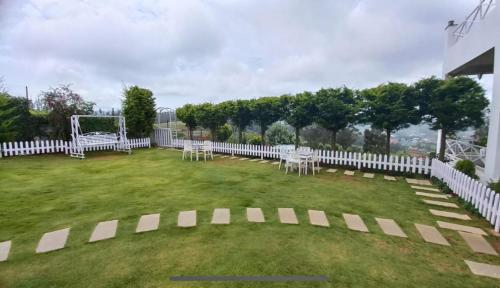 a yard with white chairs and a white fence at Orchard Valley View in Ooty