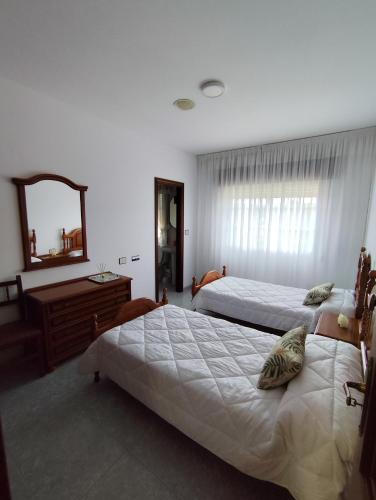 a bedroom with two beds and a dresser and a mirror at Forxan in Sanxenxo