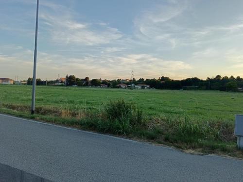 a field of green grass with a pole on the side of a road at Home Faty Fleur J&F in Oleggio