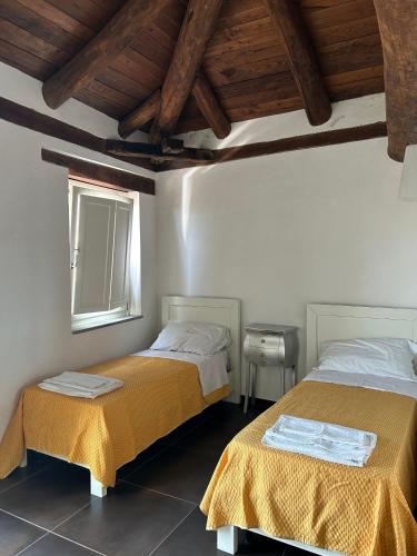 two beds in a room with wooden ceilings at Affitti brevi FESAGI in Laurino