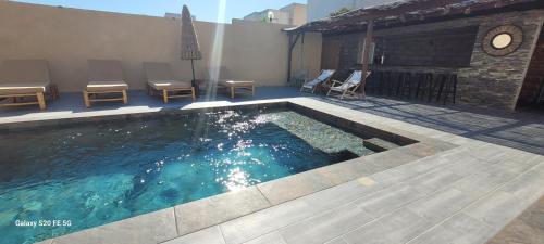 a swimming pool with chairs and a clock on a building at Villa individuelle 3 chambres - 6 pers in Calvi