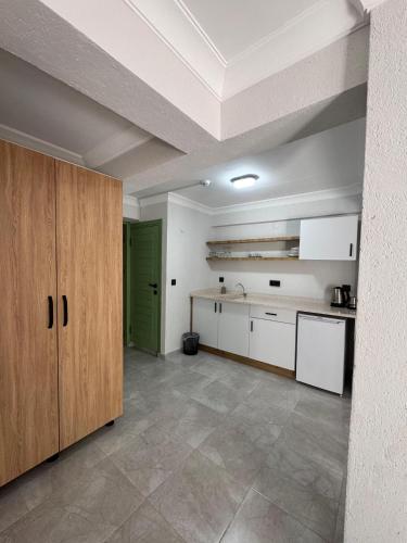 a large kitchen with white cabinets and a green door at Macaron Midi House in Ayvalık