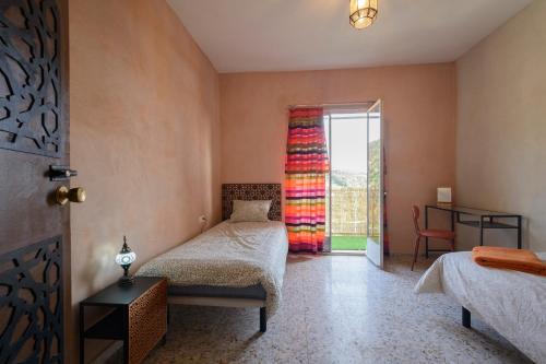 una camera da letto con due letti e una porta scorrevole in vetro di Hostal Nazarí a Cogollos De La Vega