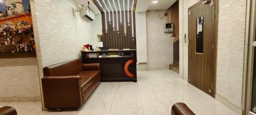 a lobby with a brown leather chair and a counter at Hotel Swarna Palace in Varanasi