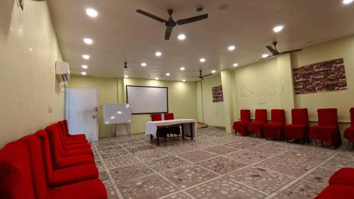 a conference room with red chairs and a table and a screen at Hotel Swarna Palace in Varanasi