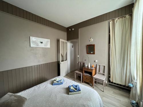 a bedroom with two beds and a table and a window at Le Papillon bleu in Asnelles