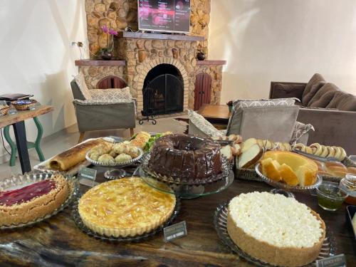 a table with pies and cakes on it with a fireplace at Pousada Doce Vida in Campos do Jordão