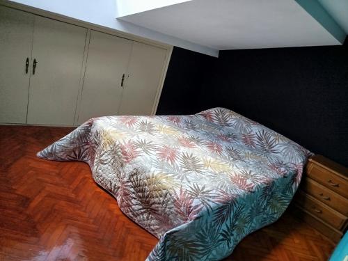 a bed in a room with a blanket on the floor at Ático Milladoiro in Milladoiro