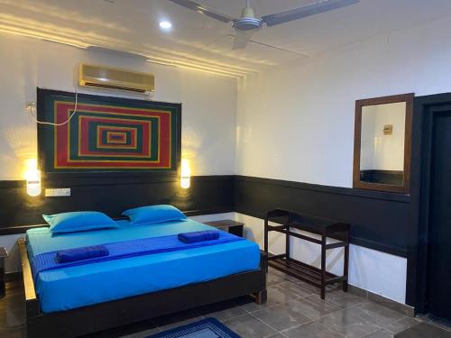 a bedroom with a bed with blue pillows and a mirror at Crown Majesty in Arugam Bay