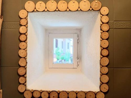 a mirror with wood slices around a window at Lucia's Wood House in Intra