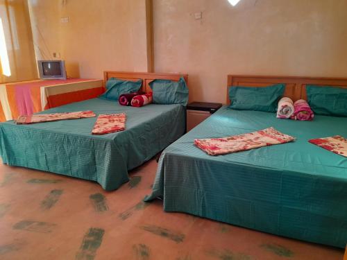 2 Betten in einem Zimmer mit grüner Bettwäsche und Beuteln darauf in der Unterkunft Nipuni sky Holidays in Nuwara Eliya