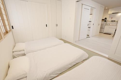 a white room with three beds in it at Bamboo Retreat Tofuku in Kyoto