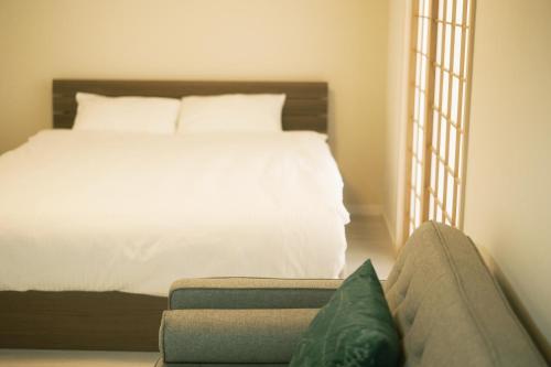 a bedroom with a white bed and a couch at Bamboo Retreat Tofuku in Kyoto
