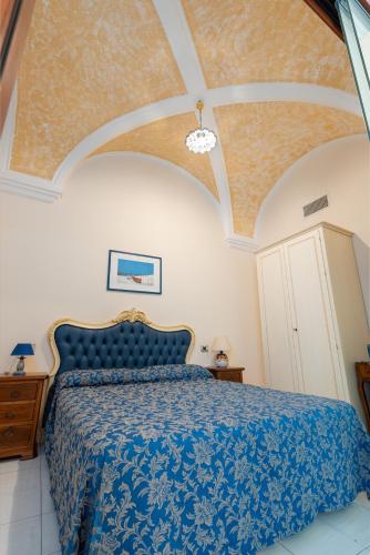 a bedroom with a bed with a blue comforter at Hotel L'Antico Convitto in Amalfi