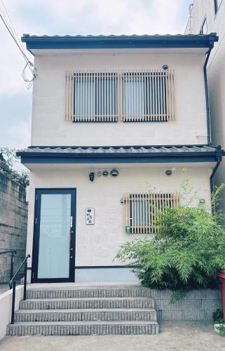 a white house with a black door and stairs at Bamboo Retreat Tofuku in Kyoto