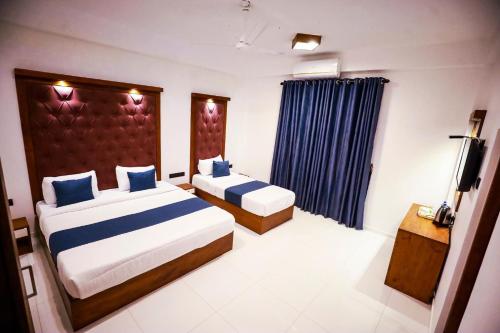 a hotel room with two beds and a television at Kudila Resort in Anuradhapura