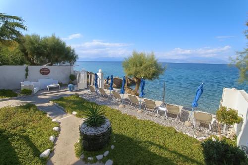 a row of chairs and umbrellas next to the ocean at Villa Constantina Apartments in Liyiá