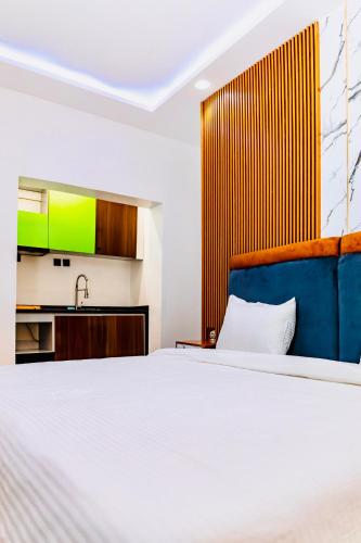 a bedroom with a white bed and a kitchen at Banora Apartments Gwarinpa in Gwarinpa