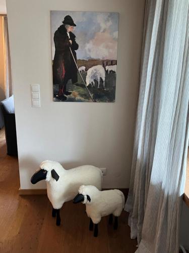 two sheep are standing in a room with a painting at Schittlerhaus in Oberstdorf