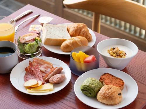 a table with plates of breakfast food on it at Mitsui Garden Hotel Fukuoka Gion in Fukuoka