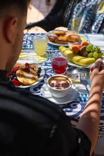 a man sitting at a table with breakfast foods at Hotel L'Antico Convitto in Amalfi