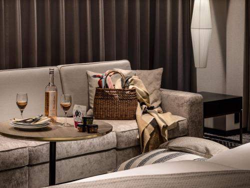 a living room with a couch with a table and wine glasses at Mitsui Garden Hotel Fukuoka Gion in Fukuoka