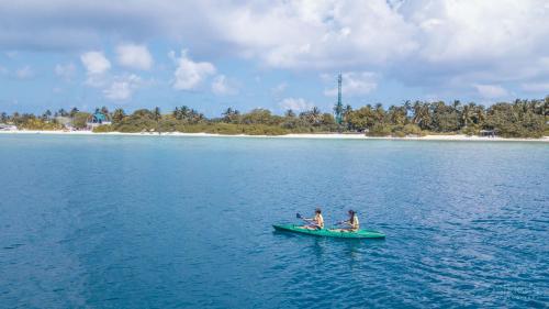 two people on a boat in the water with an island at Aseria Beach in Ukulhas