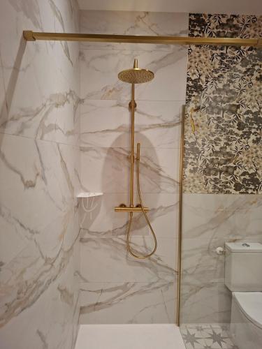 a shower in a bathroom with a marble wall at La Glycine in Luçon