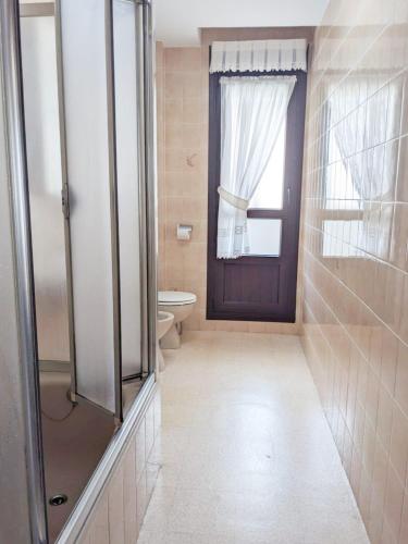 a bathroom with a shower and a toilet and a window at Candás Suites in Candás