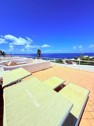 a deck with tables and chairs and the ocean at Hotel Albatros in Ischia