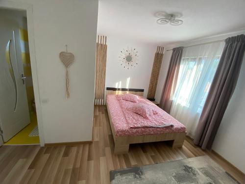 a bedroom with a pink bed and a window at Casa Valex in Tohanu Nou