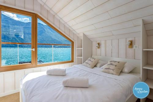 a bedroom with two beds and a large window at Chalet Coquillage Waterfront Escape On Lake in Doussard